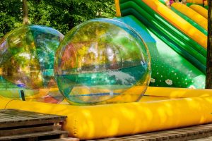 Aqua zorbing. Colorful water walking balls. Water activity for kids. Children playing together and having fun inside large inflatable sphere in a pool.