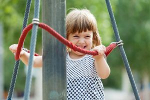 laughing girl climbing at ropes on playground